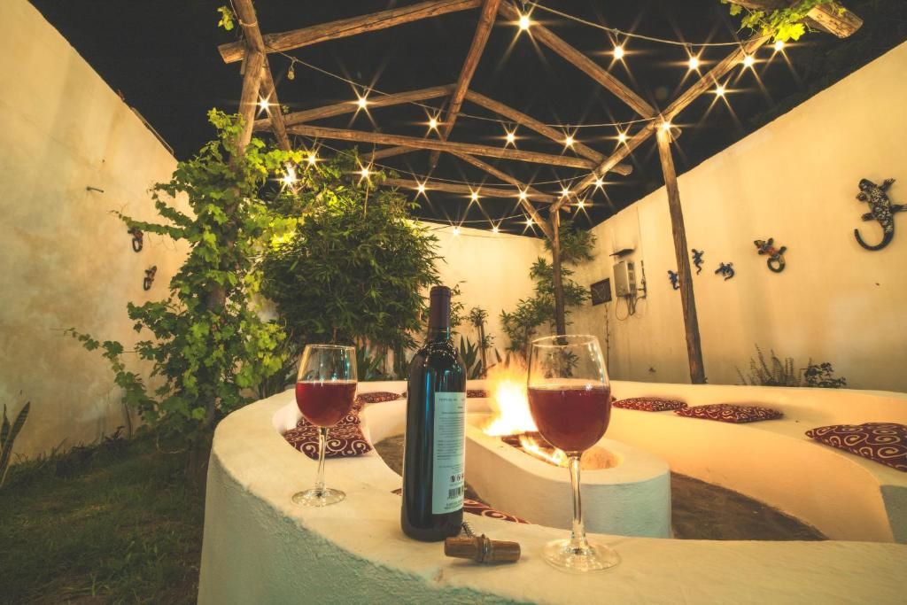 A cozy outdoor seating area with a fire, two wine glasses, and a bottle of wine.