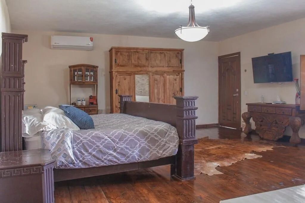 Un dormitorio con cama de madera, armario, televisor y aire acondicionado.