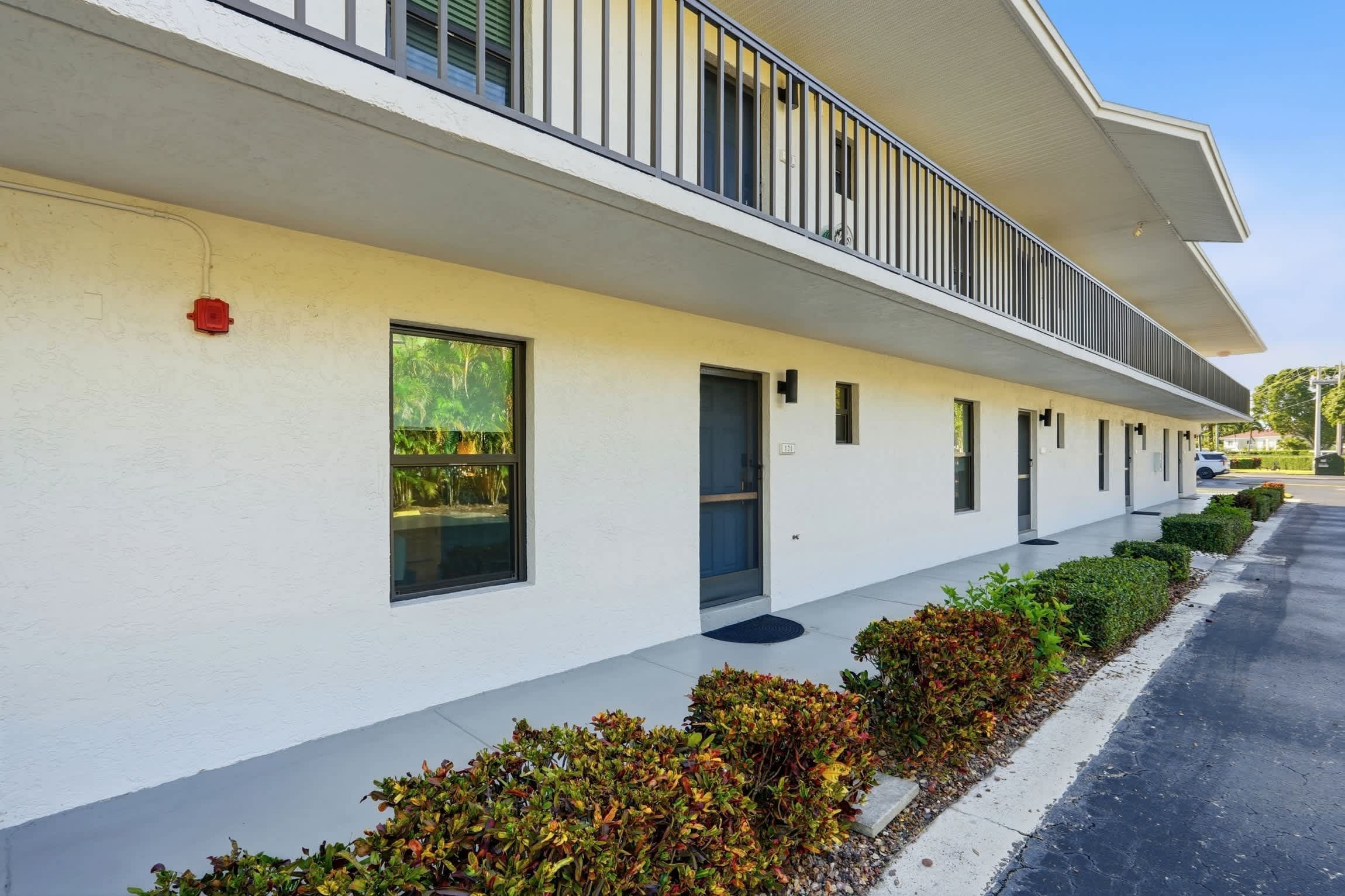 A modern building with a white facade, a covered walkway, and a row of windows.