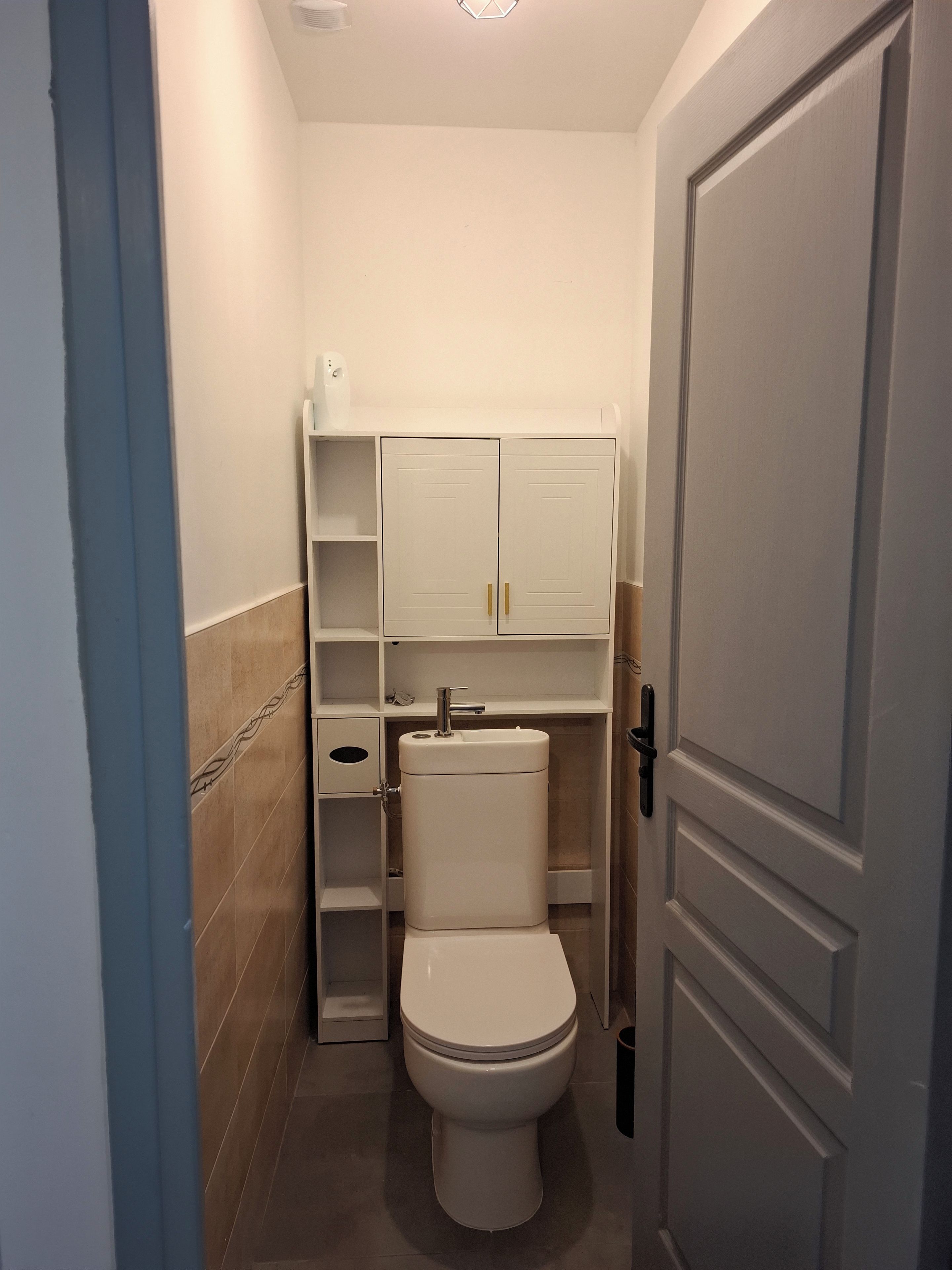 A compact bathroom with a toilet, a sink, and a cabinet.