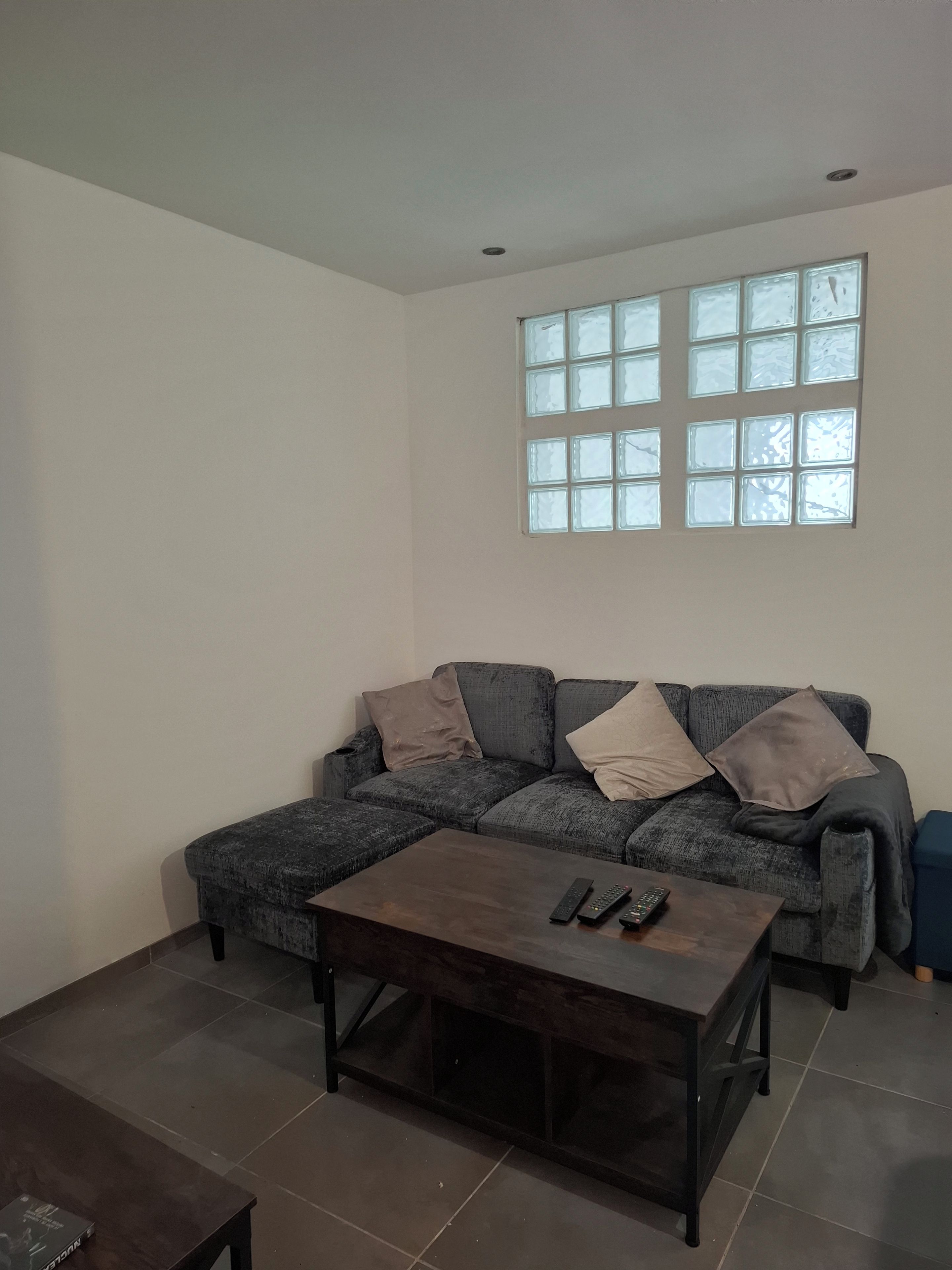 Una sala de estar con un sofá gris, una mesa de centro oscura y un ventanal con múltiples divisiones.