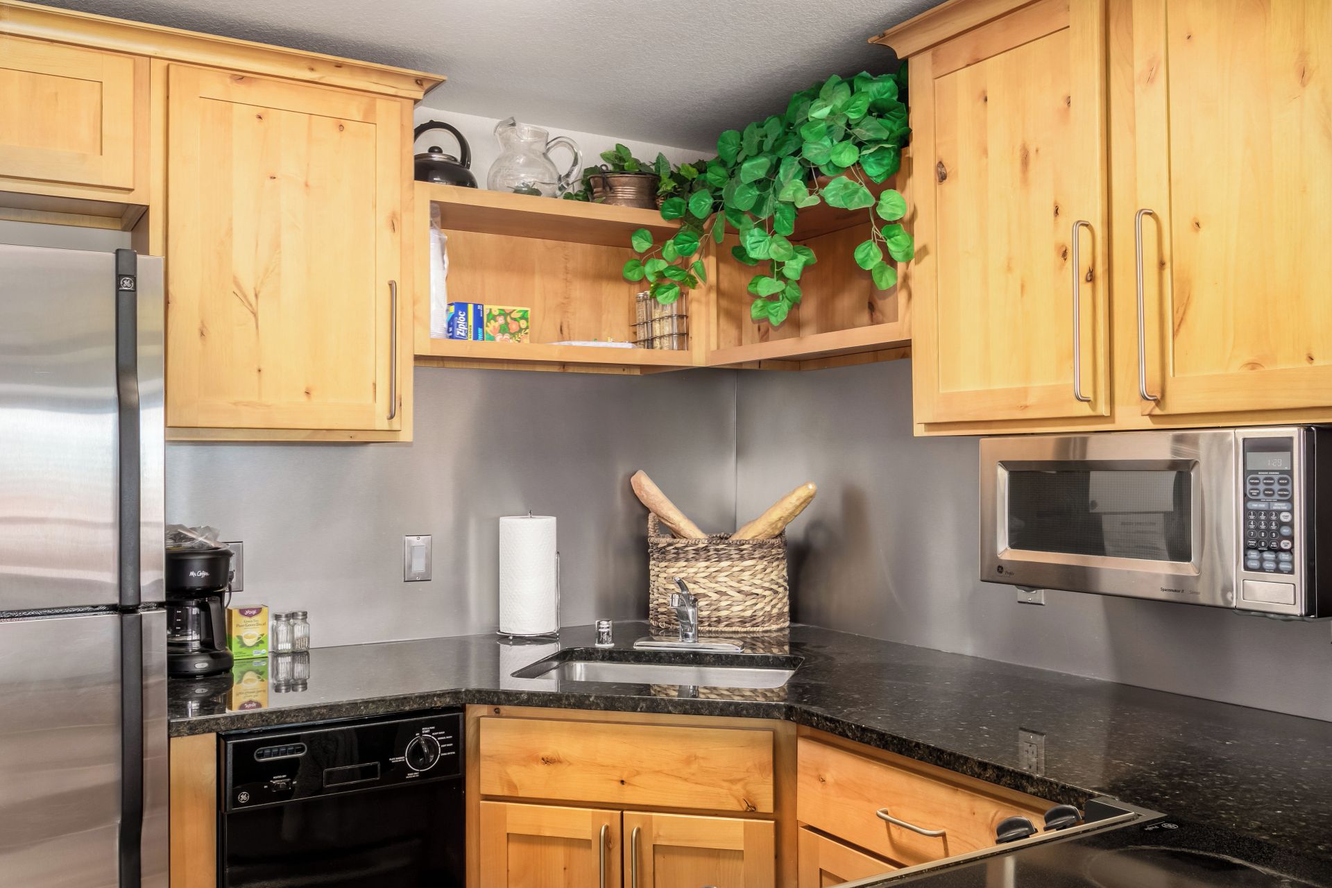 A kitchen with wooden cabinets, a stainless steel refrigerator, a microwave, and a sink.