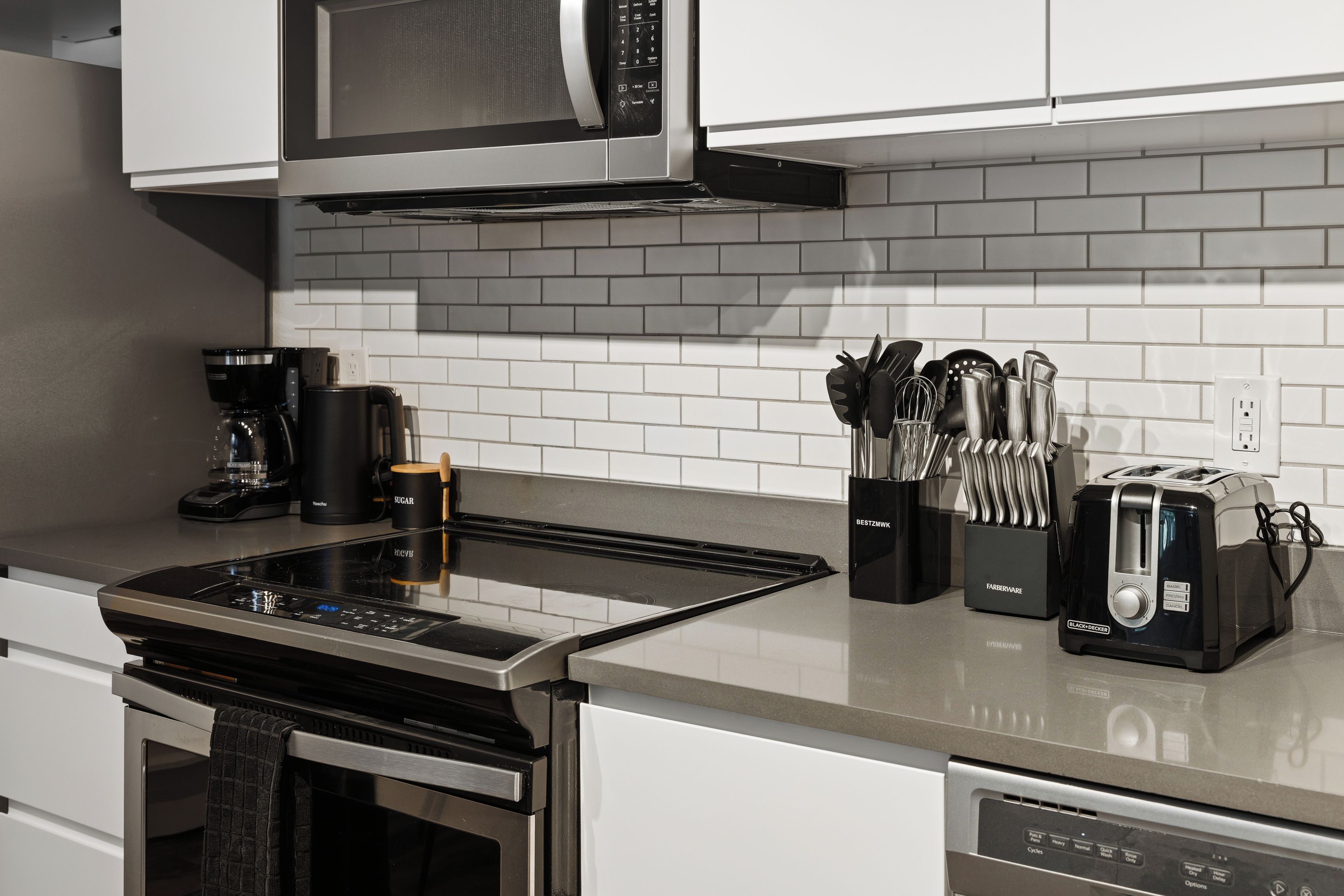A modern kitchen with a built-in microwave, a coffee maker, a toaster, and a knife block.