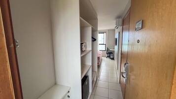 A narrow hallway with a bed, a chair, and a desk area.