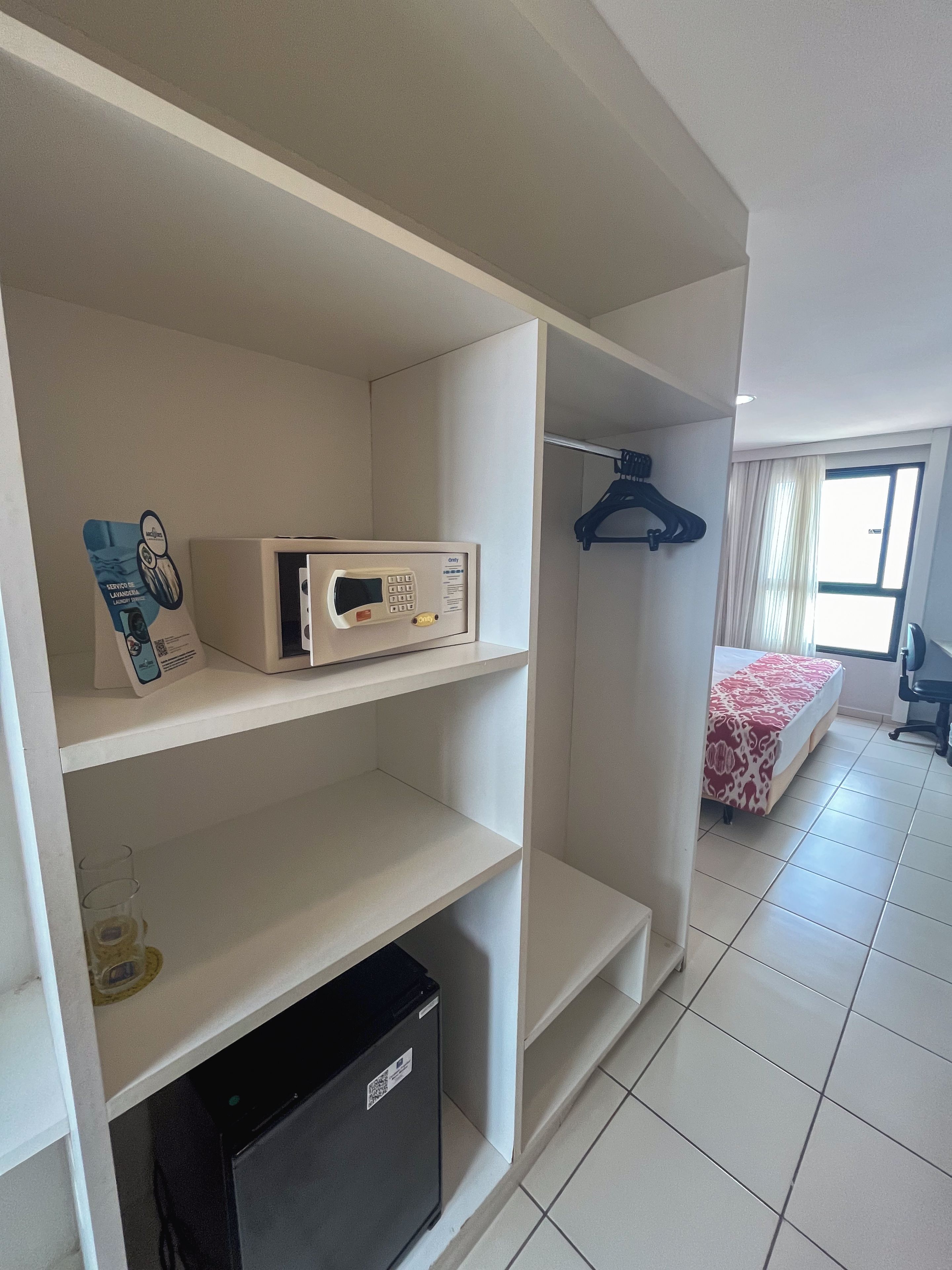 Una habitación de hotel con cama, armario, microondas y refrigerador pequeño.