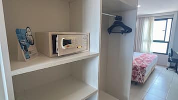 Una habitación de hotel con cama, armario, microondas y refrigerador pequeño.
