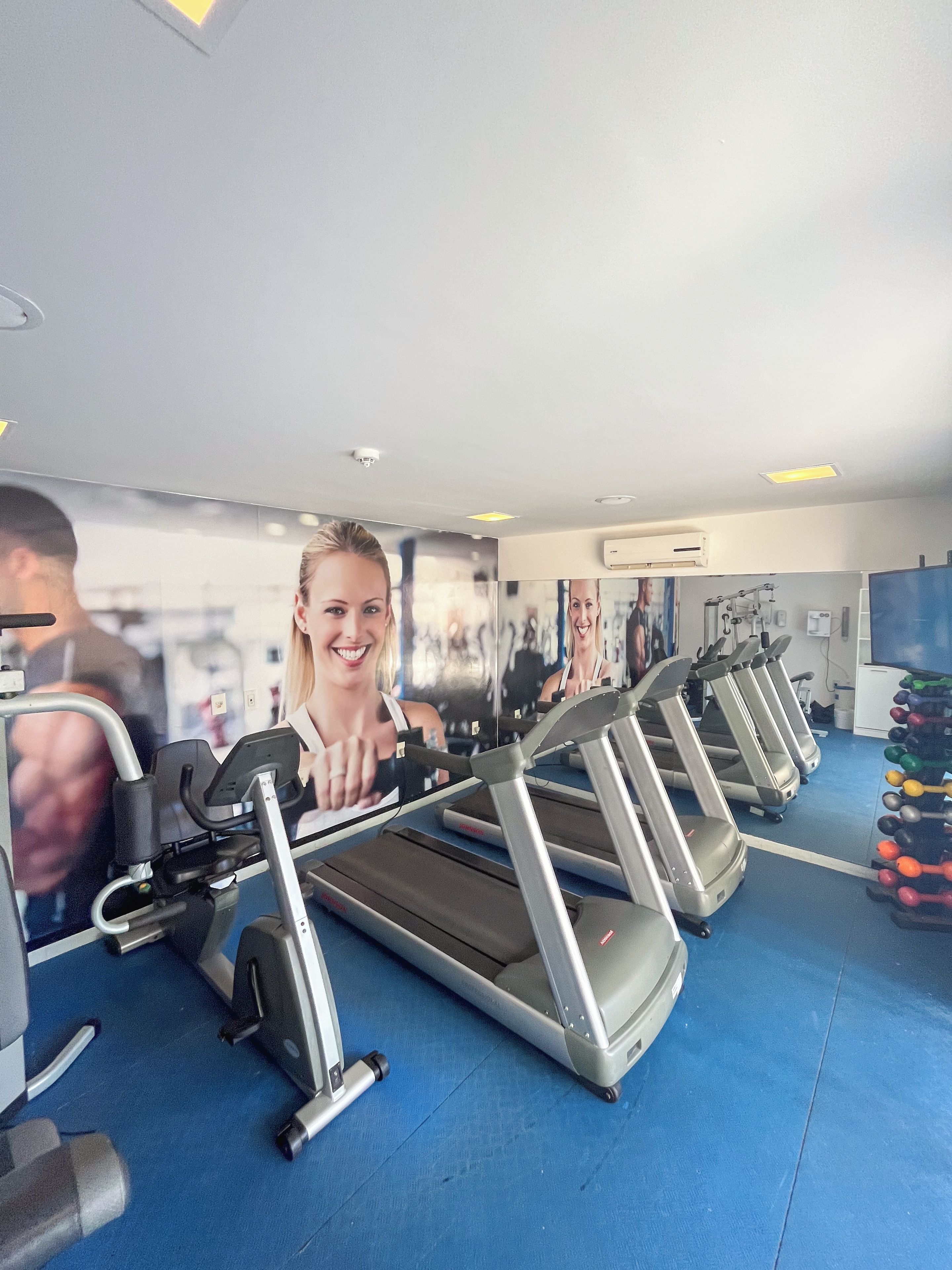 A gym with treadmills, weight machines, and a blue floor.