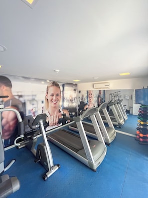 A gym with treadmills, weight machines, and a blue floor. - Flats Vista Mar (Natal)