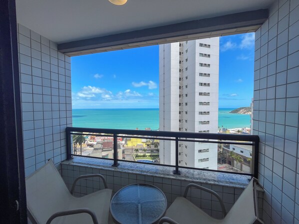 A balcony with a view of the ocean and a tall building. - Flats Vista Mar (Natal)