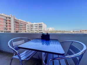 A rooftop terrace with a table and chairs, overlooking a cityscape with buildings. - Elegant 2BR/2BA Condo w/ Rooftop Pool, Cabo (Cabo San Lucas)