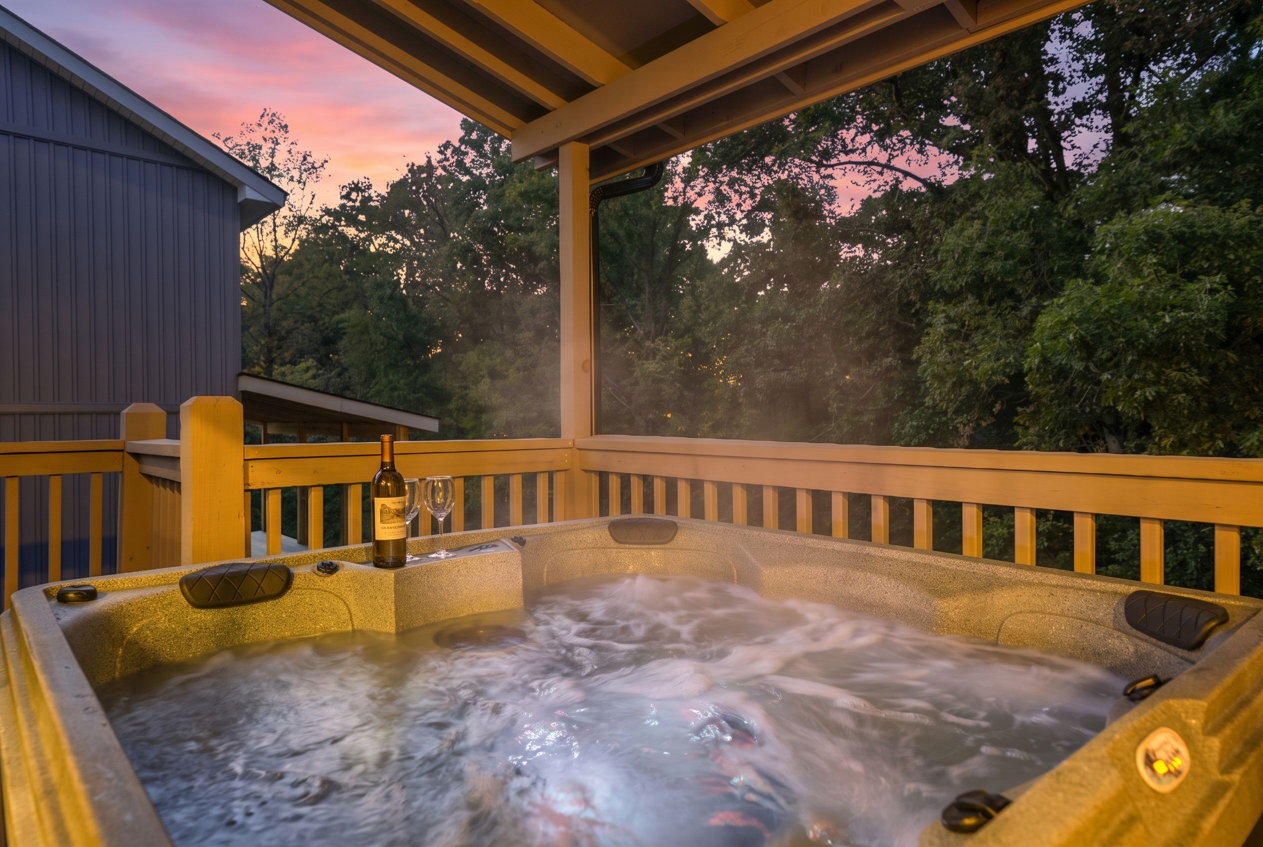 A hot tub with a wooden deck and a view of trees and a sunset.