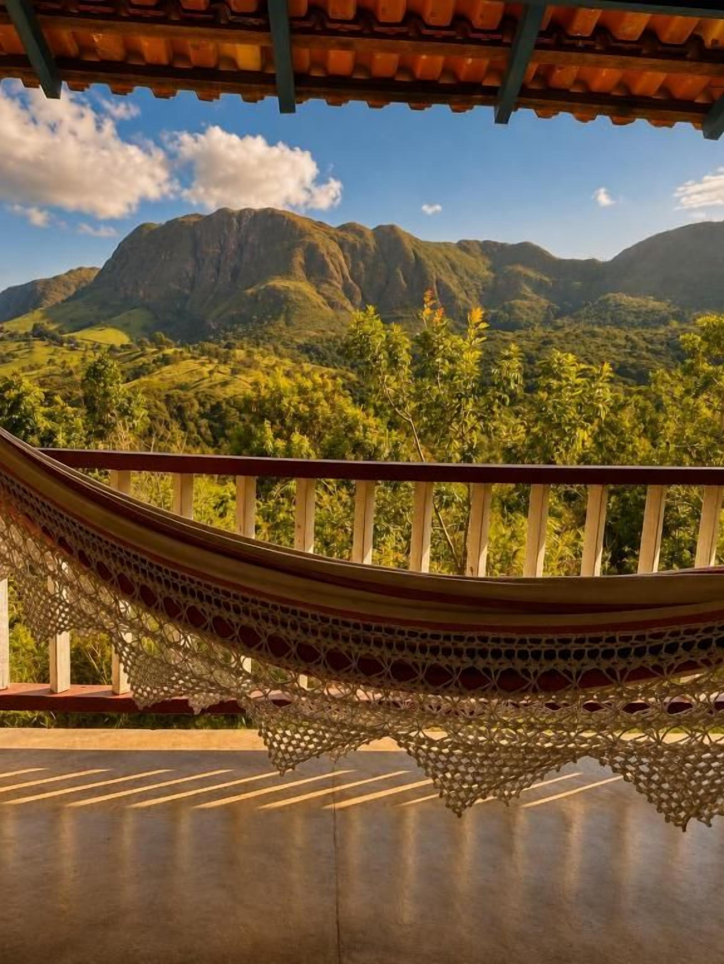 Una hamaca colgada sobre un balcón con vistas a montañas y vegetación.