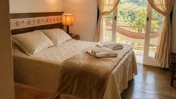 A bedroom with a bed, bedside table, lamp, and curtains.