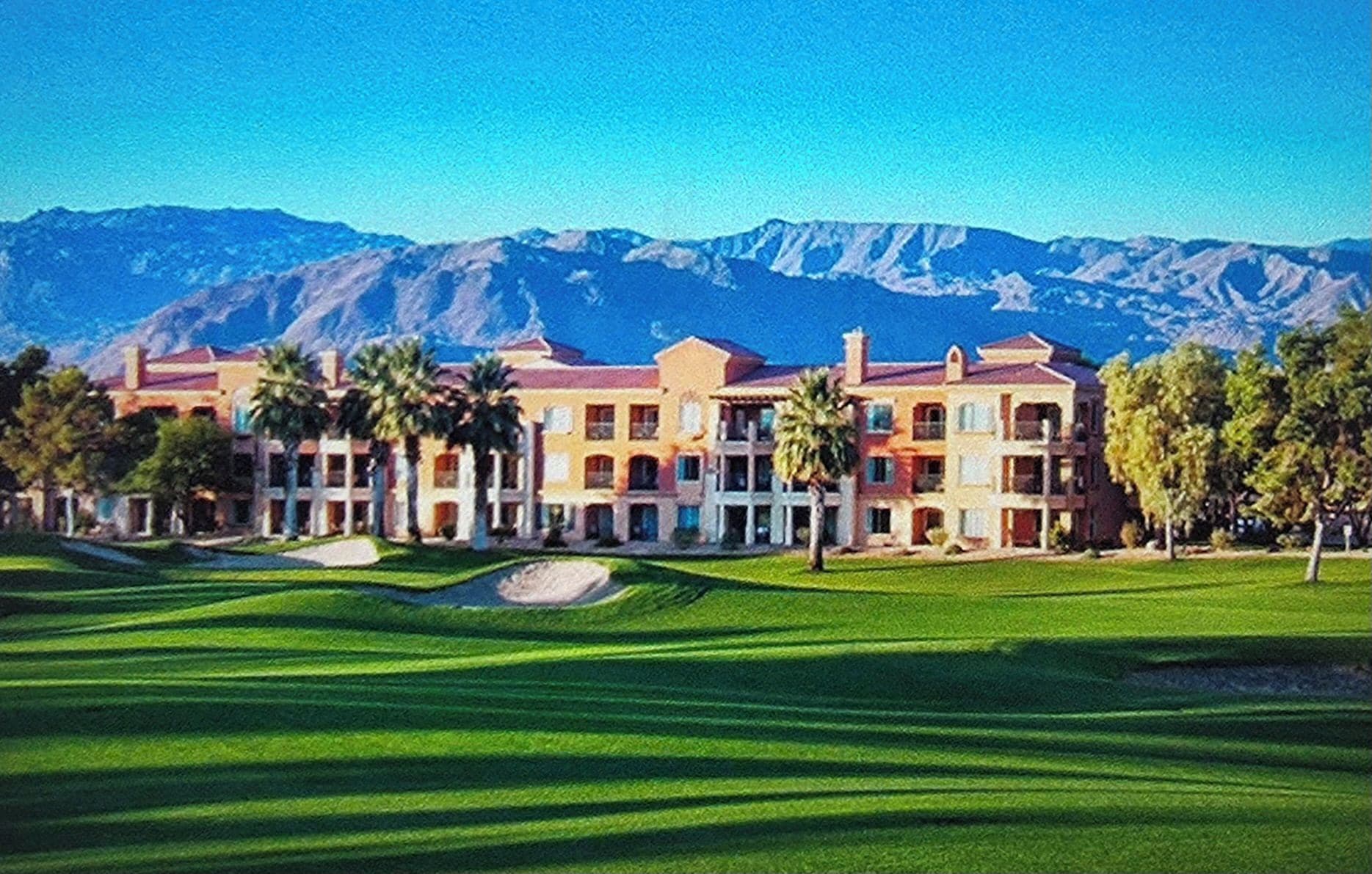 A hotel with multiple buildings, a well-maintained lawn, and mountains in the background.