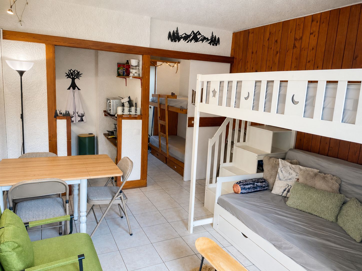 A compact room with a bunk bed, a small dining table, a chair, and a bench.