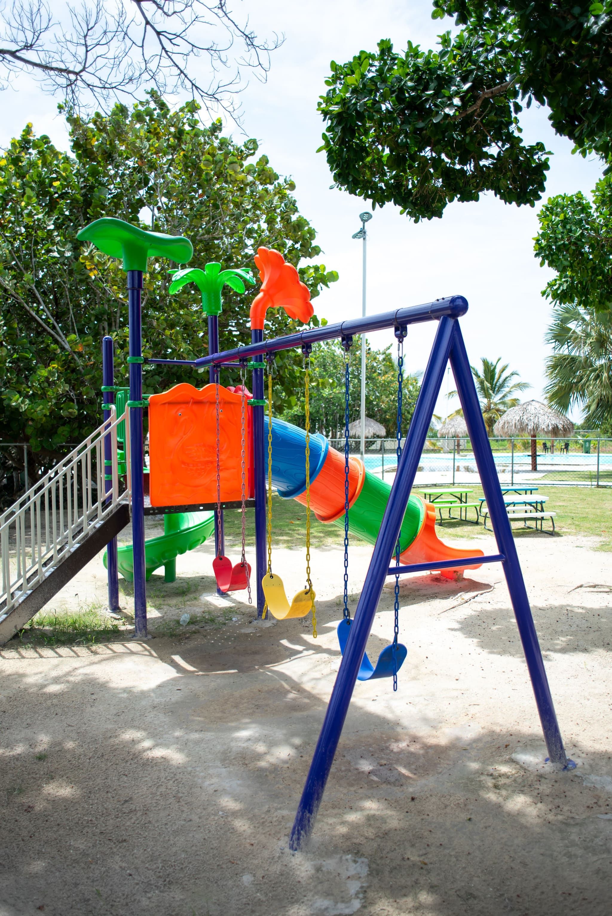 Un parc infantil amb cadira d'oscileu i tobogans.