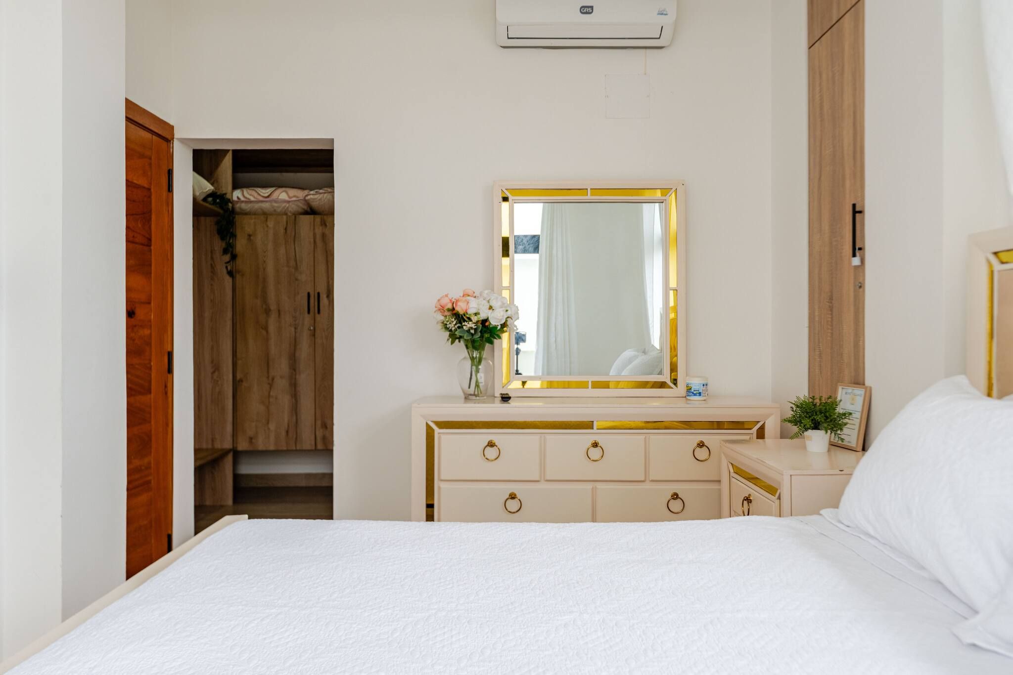 Une chambre à coucher comprenant un lit, une commode avec des tiroirs, un miroir et une armoire.