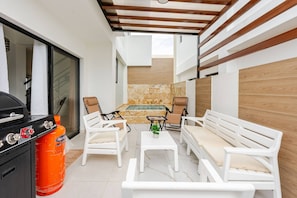 A patio area with a barbecue grill, two white sofas, a small table, and a hot tub. - Beautiful Place 12 Minutes From Airport (Punta Cana)
