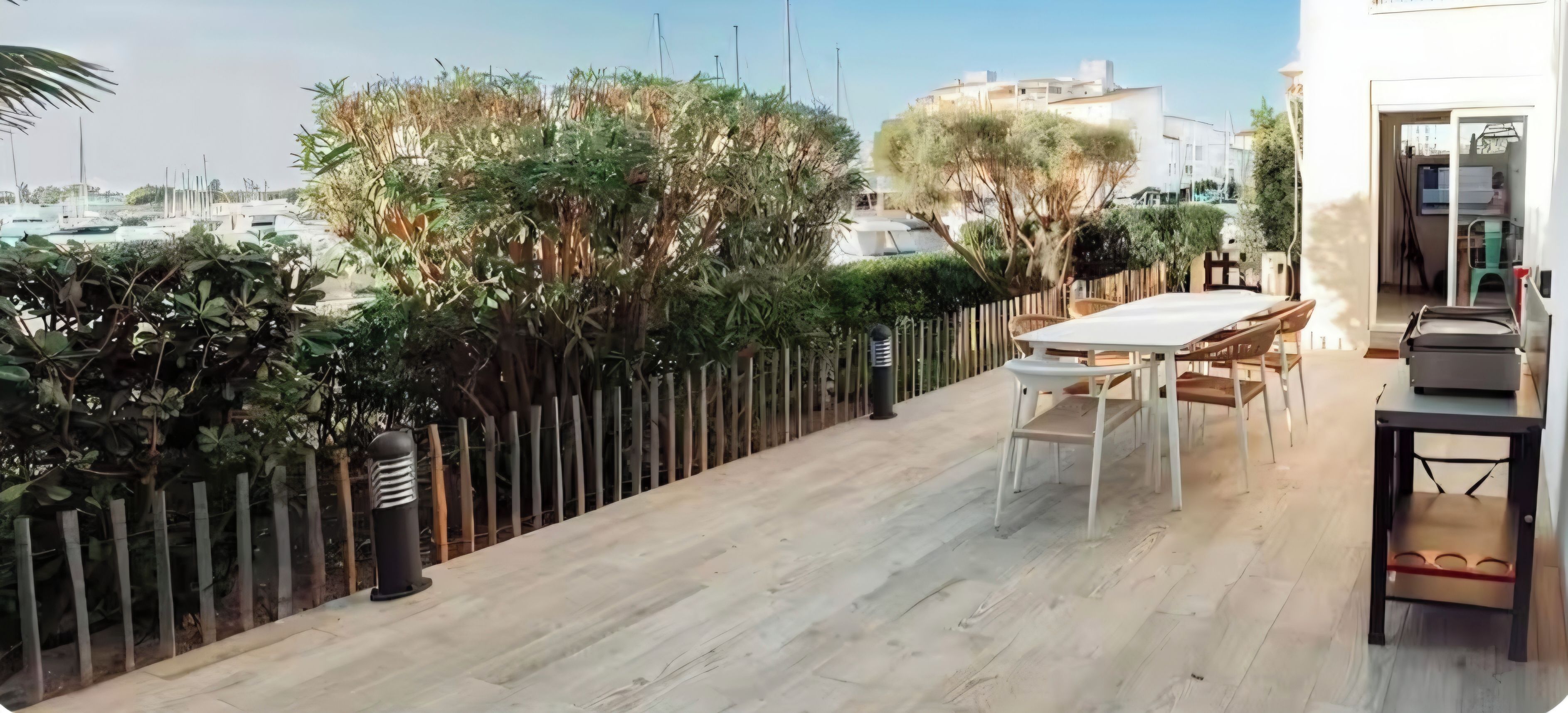 A balcony with a table and chairs, a view of the sea, and a wooden fence.