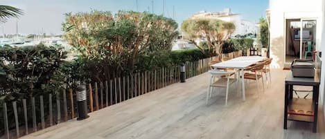 A balcony with a table and chairs, a view of the sea, and a wooden fence.