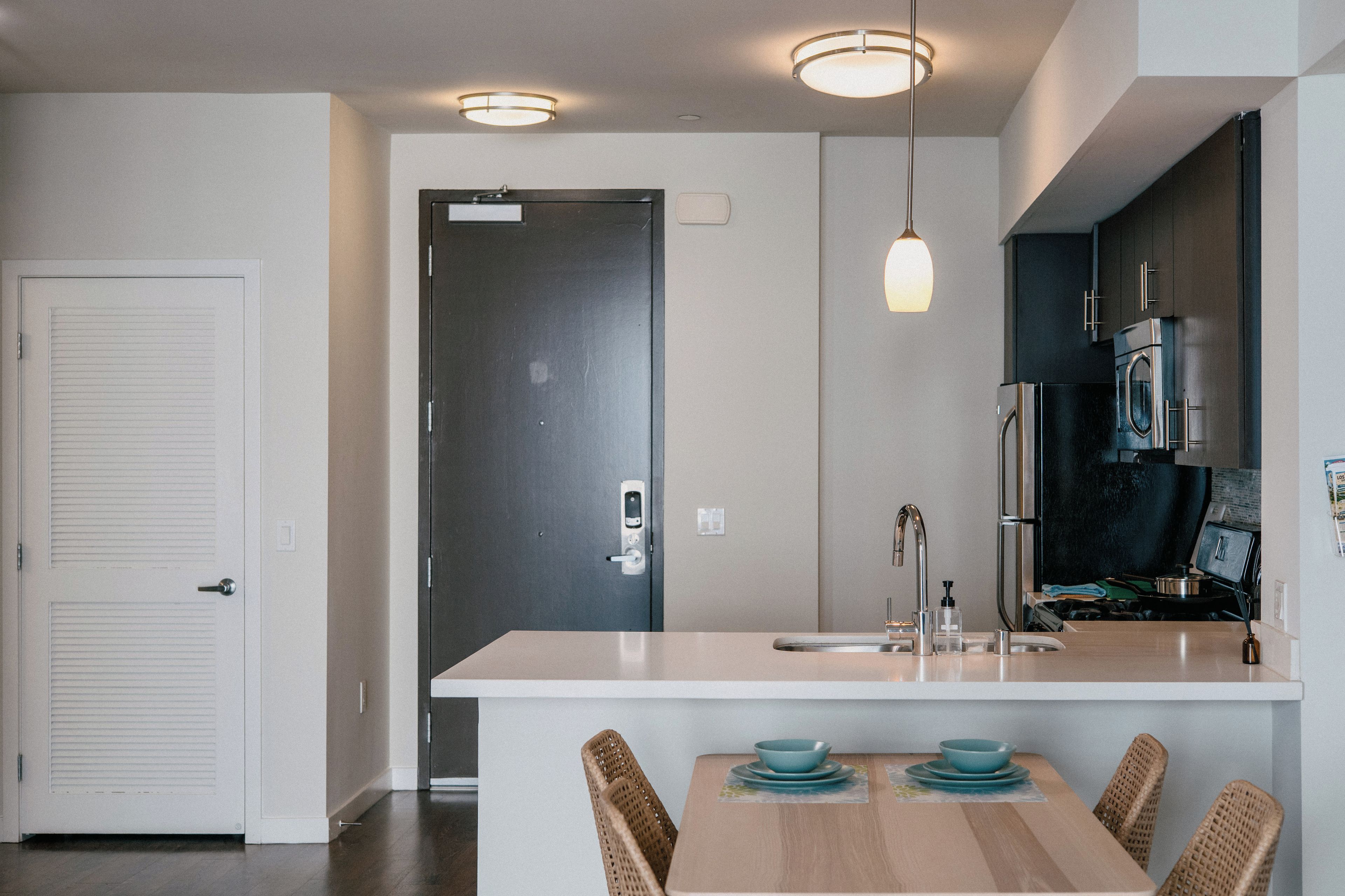 A modern kitchen with a central island, stainless steel appliances, and a dining area with wicker chairs.