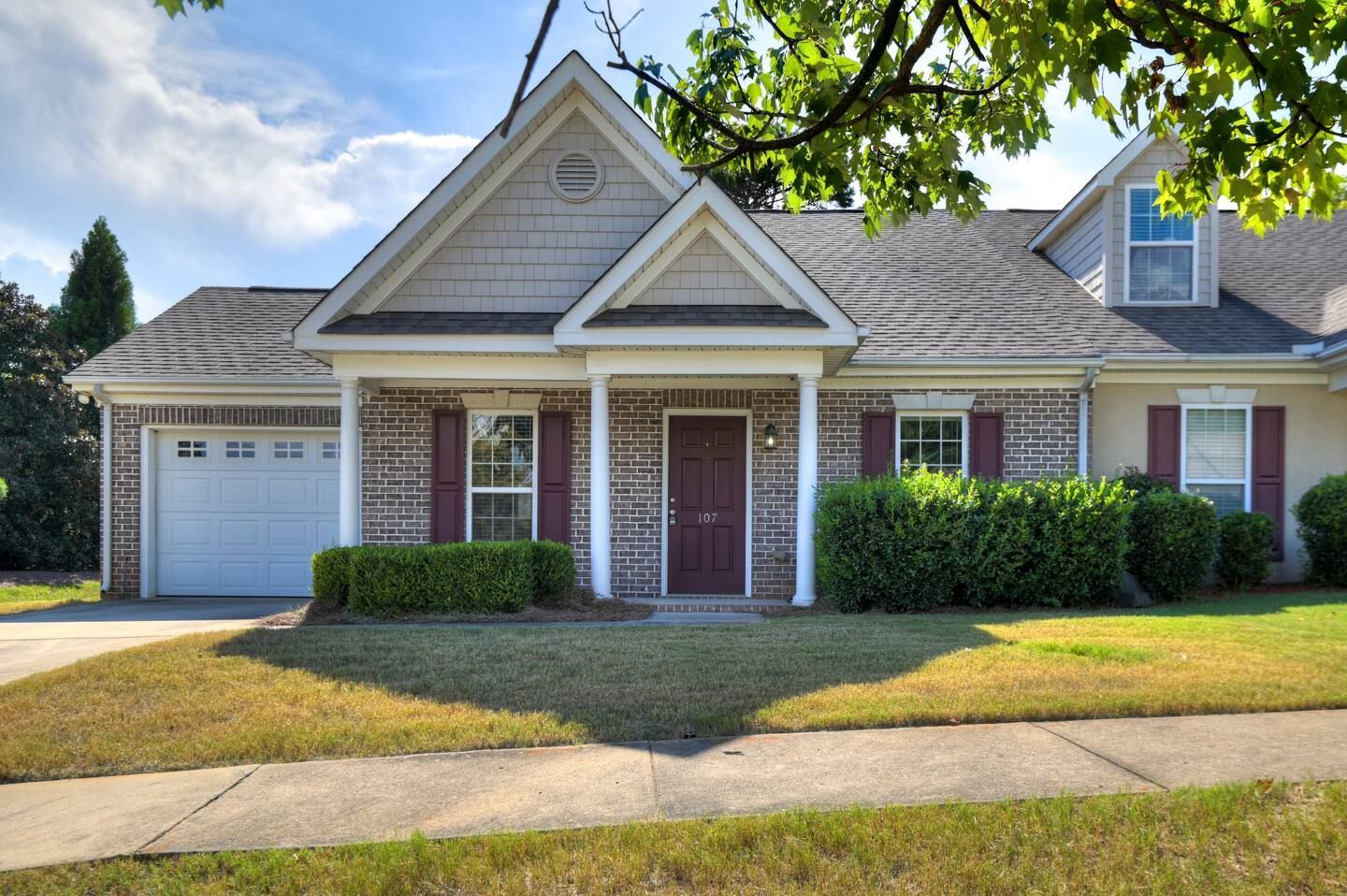 A two-story residential house with a front porch, a garage, and a well-maintained lawn.