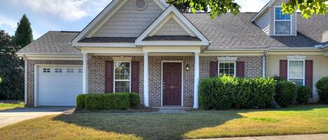 A two-story residential house with a front porch, a garage, and a well-maintained lawn.