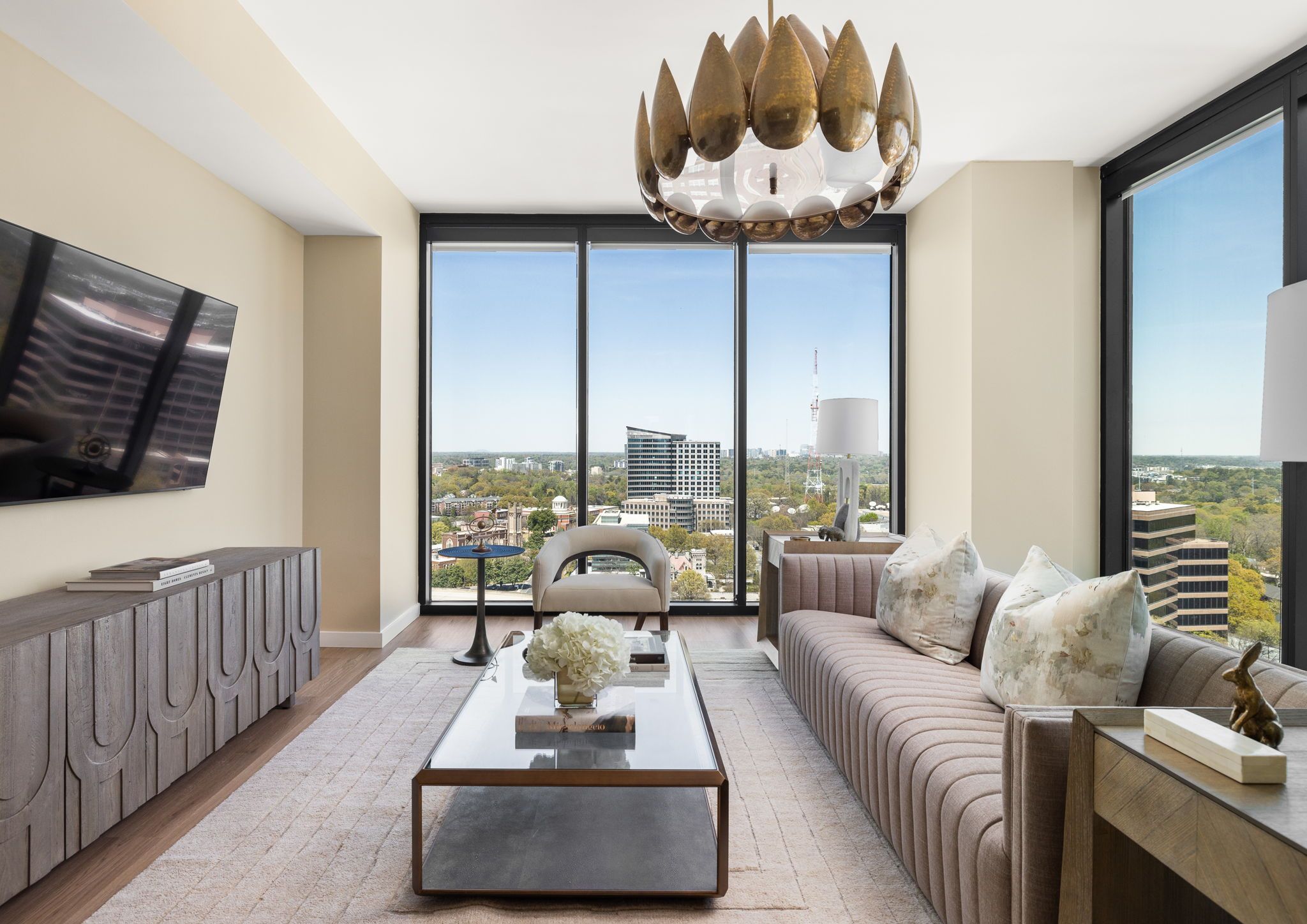 A modern living room with a sofa, coffee table, and a large TV on the wall.