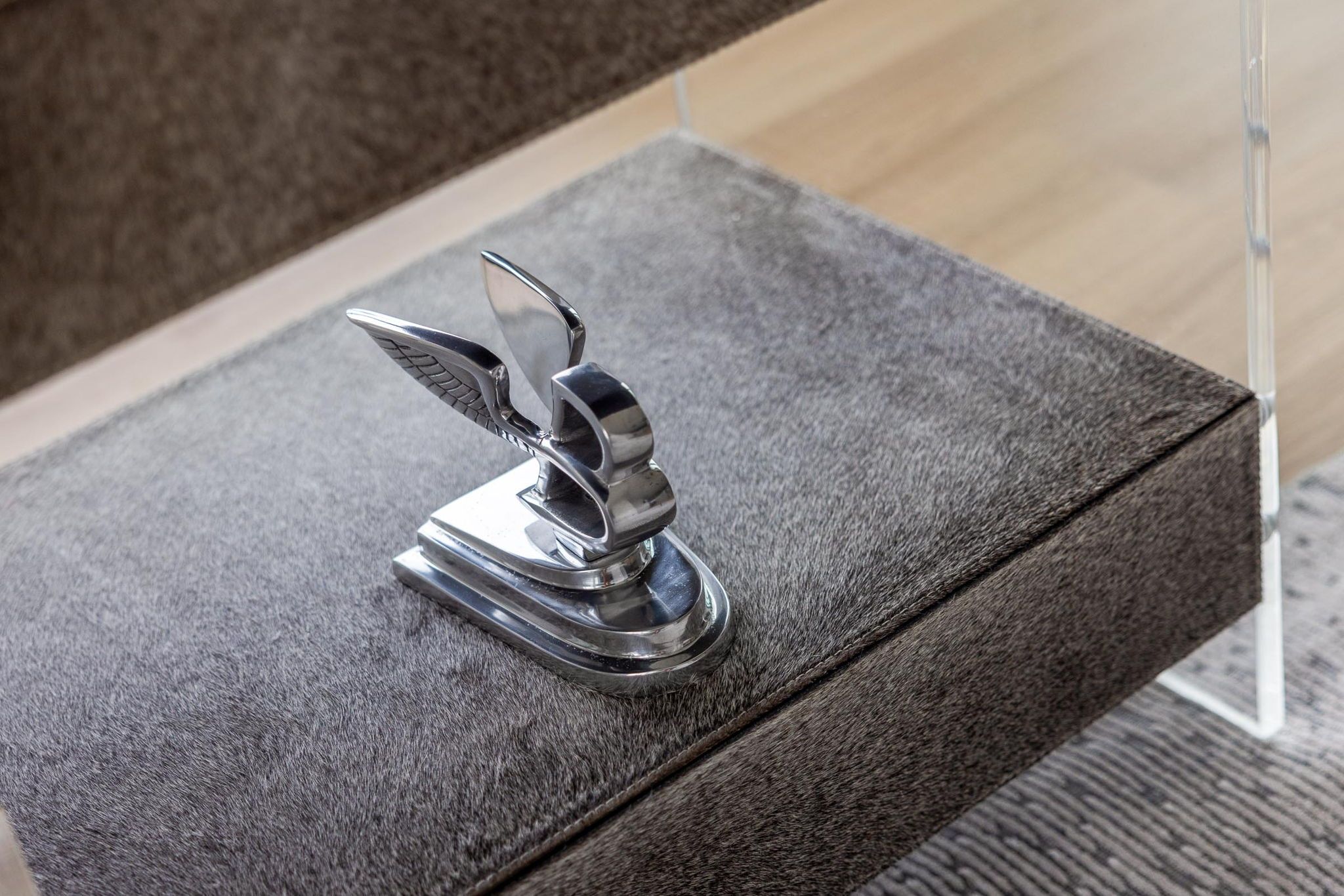 A metallic object with a curved design, possibly a decorative piece, placed on a textured surface.