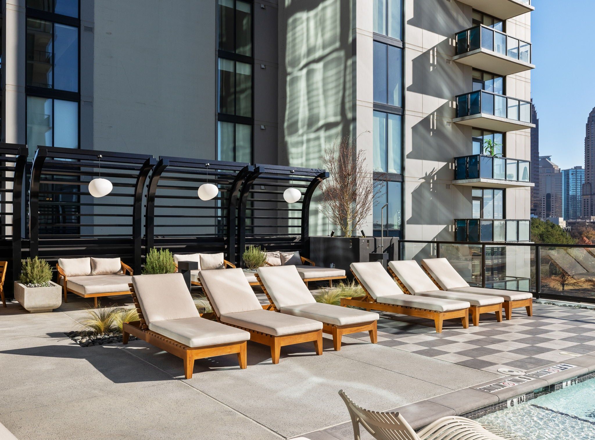 A rooftop pool area with lounge chairs and a pergola.