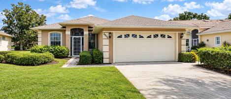 A single-story house with a garage, a well-maintained lawn, and a clear sky.