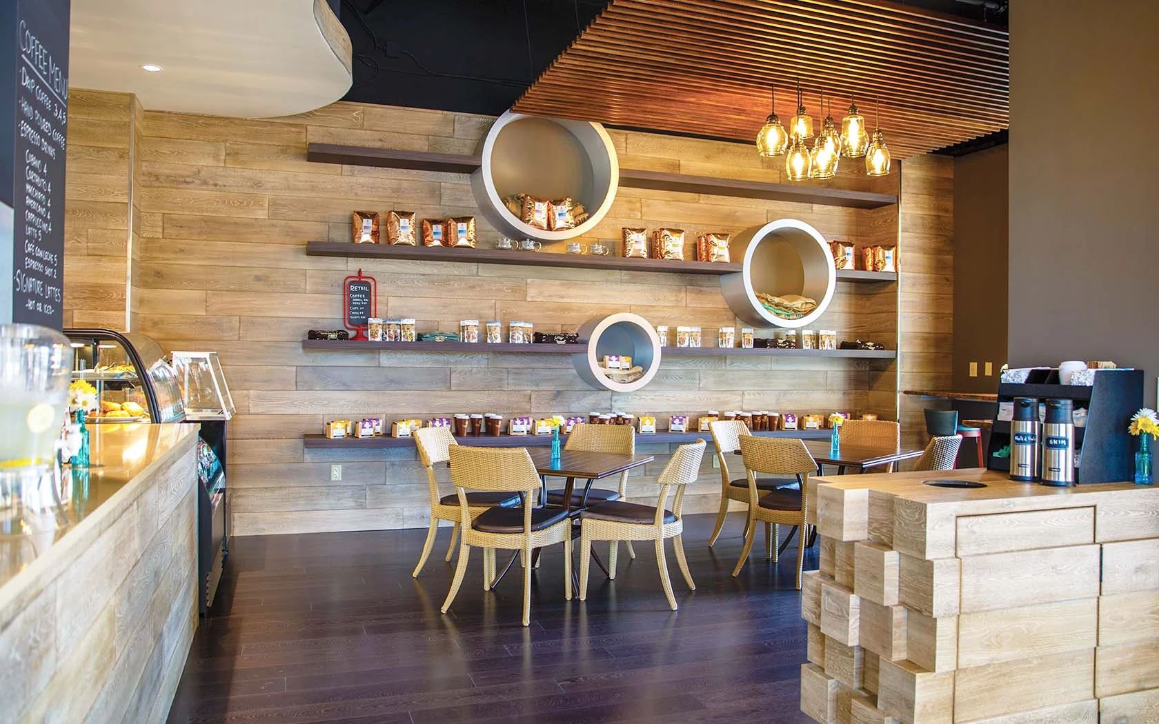 A coffee shop interior with wooden walls, round display shelves, wicker chairs, and a coffee bar.