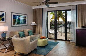 A hotel room with a sofa, ottoman, and artwork on the wall. - Accessible 1BR Suite w/ Kitchen | Pools & Hot Tub (Naples)