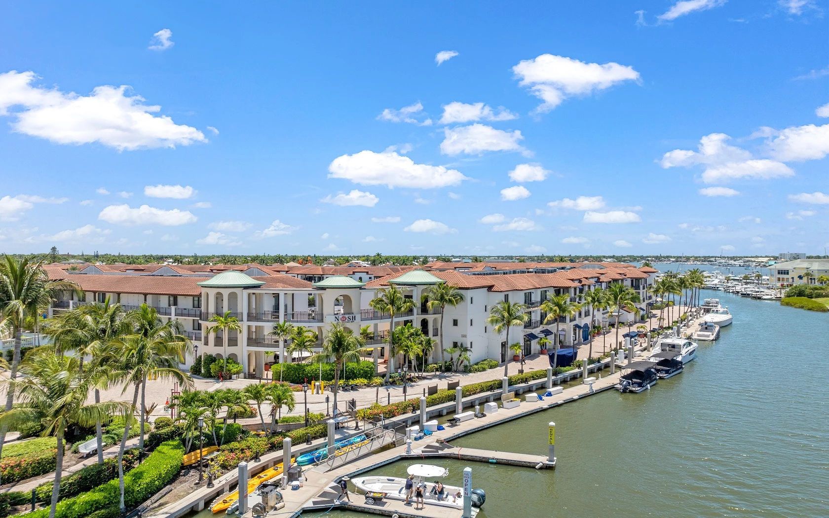 A marina with boats docked, a waterfront promenade, and a row of buildings with a consistent architectural style.