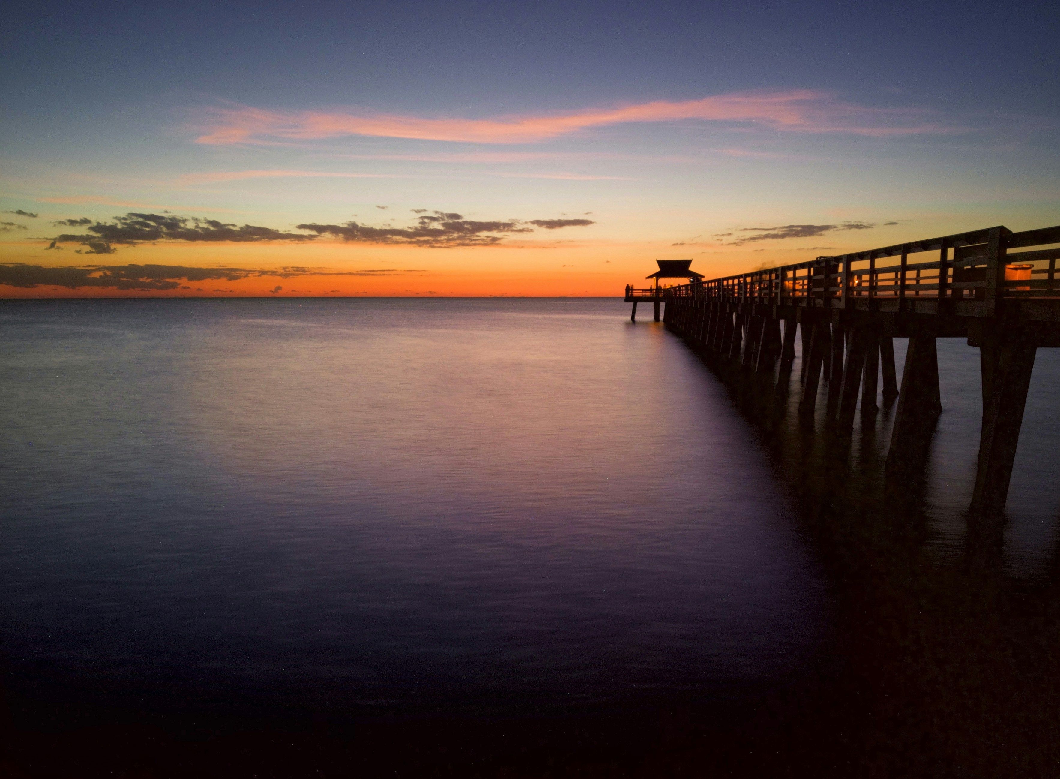 A pier extending into calm waters at sunset.