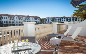 Eine Dachterrasse mit Tisch für zwei Personen, Liegestühlen und Blick auf Hotelgebäude.