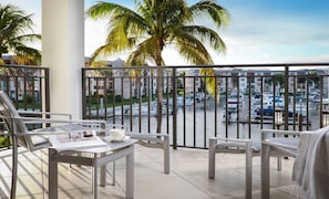 Un balcon donnant sur une marina, avec une table sur laquelle est posé un magazine, une chaise et une serviette.