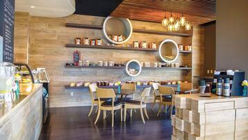 A coffee shop interior with wooden walls, round display shelves, wicker chairs, and a coffee bar.