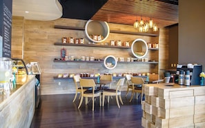 L’intérieur d’un café, avec des murs en bois, des étagères rondes, des chaises en osier et un comptoir à café.