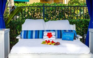 Un letto con un cuscino a righe blu, un piatto di frutta e un cartello che indica una stanza riservata per un ospite privato o un membro.