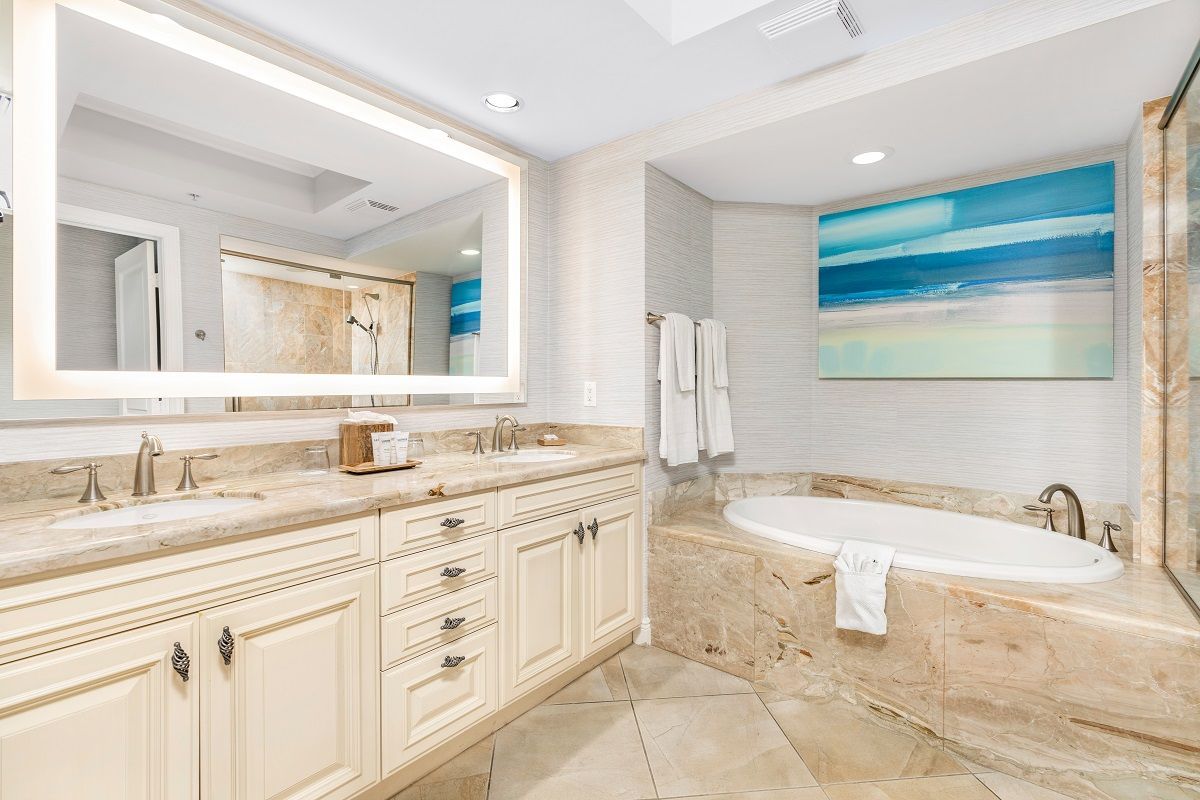 Un bagno moderno con uno specchio grande, una vasca da bagno e un quadro appeso al muro.