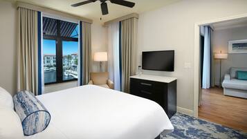 A hotel room with a bed, a TV, a desk, and a view of the city.