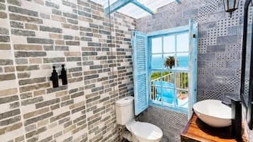 A bathroom with a skylight, a toilet, a sink, and a view of the outdoors.