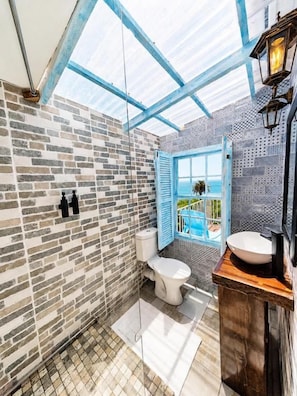 Un baño con tragaluz, inodoro, lavamanos y vistas al exterior.