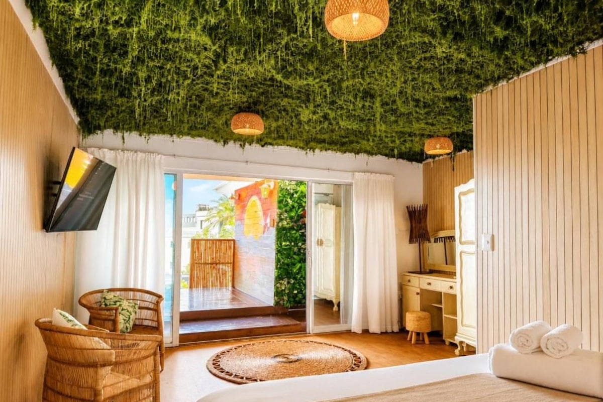 Una habitación de hotel con cama, escritorio, televisor y vistas al exterior.