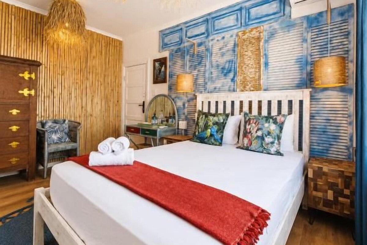 Una habitación de hotel con cama, mesita de noche y un muro con paneles decorativos.