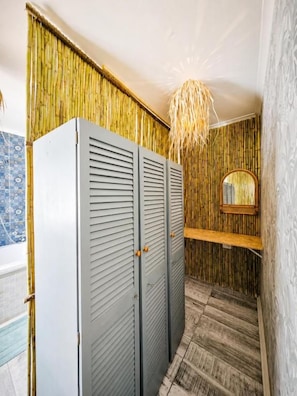 Un baño con pared de bambú, un espejo y una lámpara en el techo.