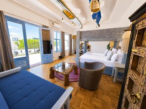 Habitación de hotel moderna con una cama grande, un sofá, una mesita y vistas al exterior.