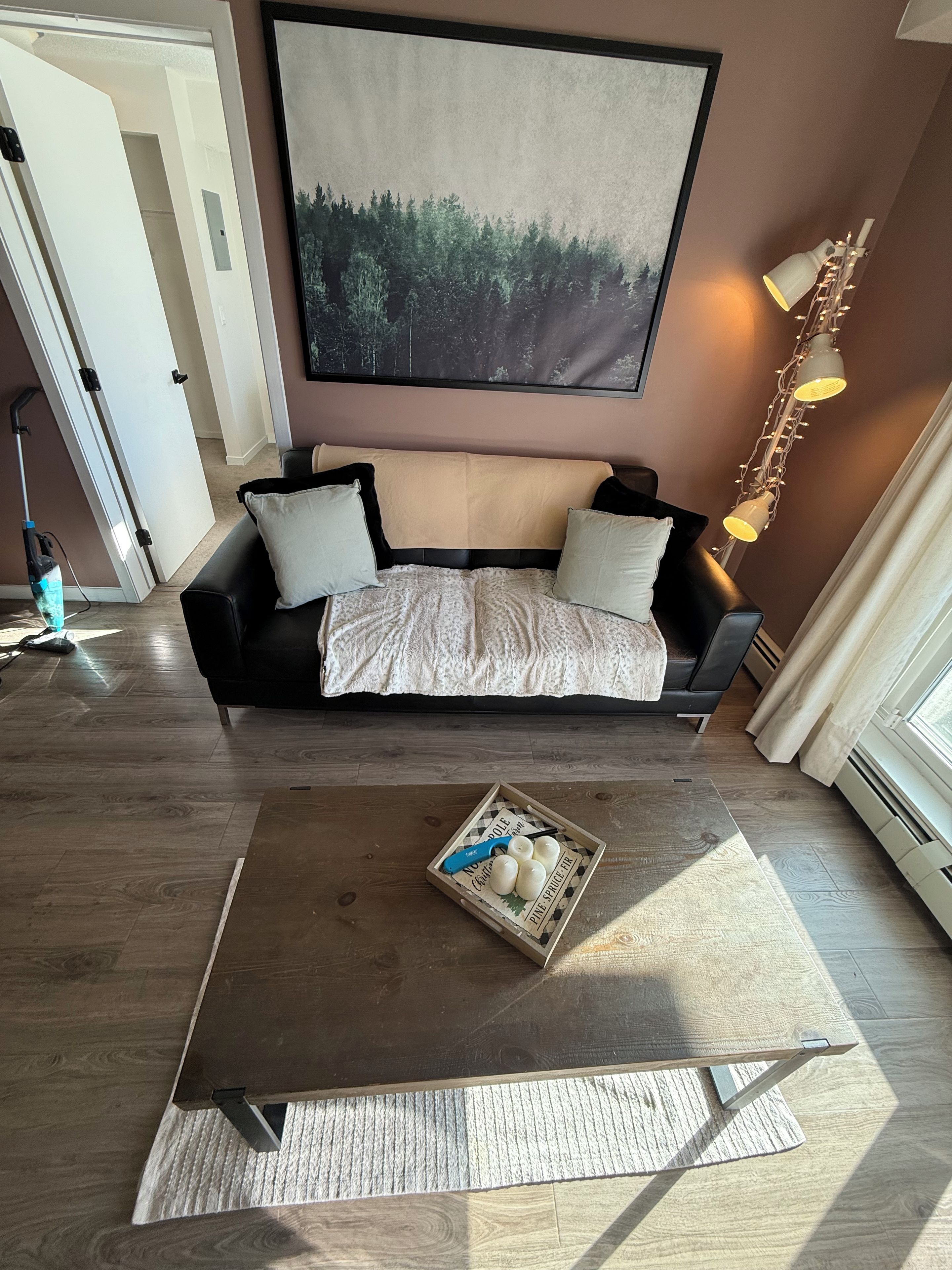 A modern living room with a sofa, a coffee table with decorative items, and a large abstract painting on the wall.