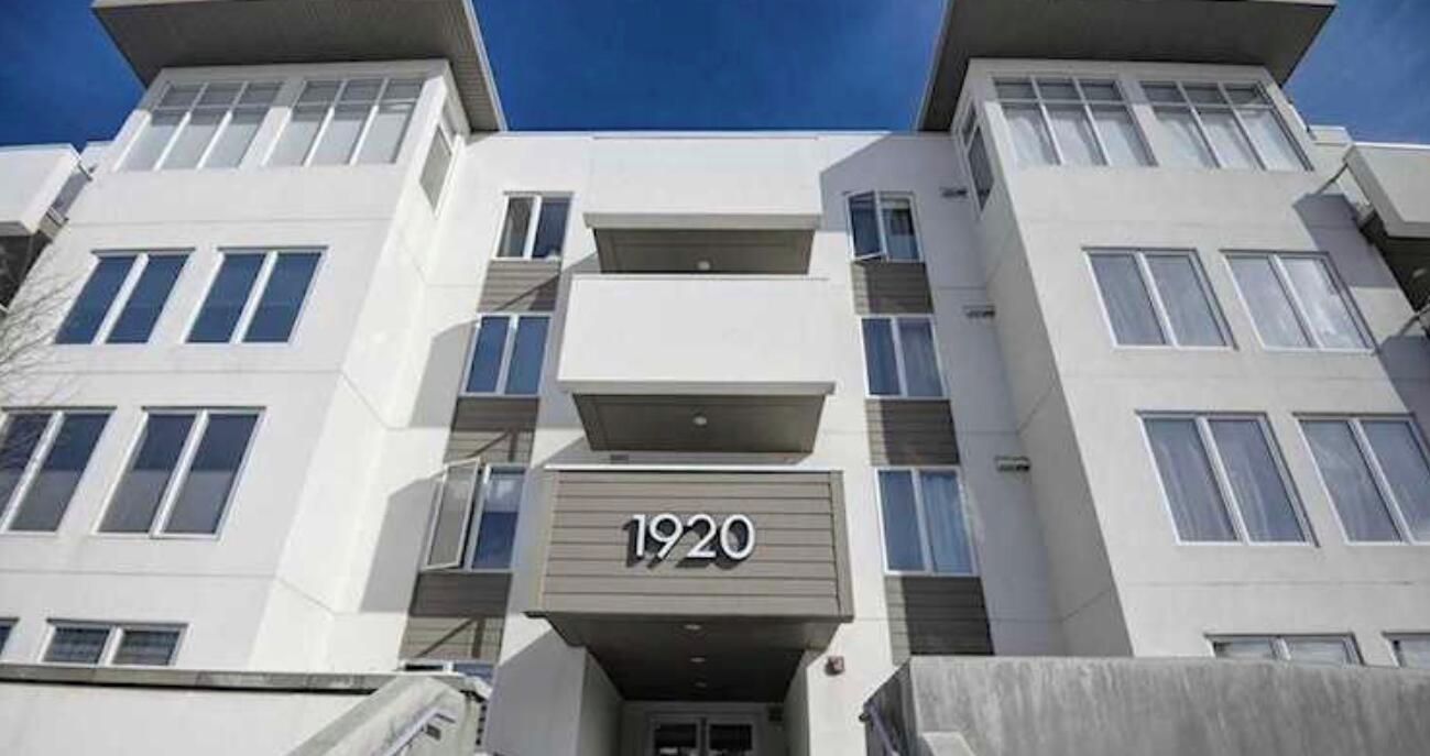 A modern building with a flat facade, multiple balconies, and a prominent number '1920' sign.